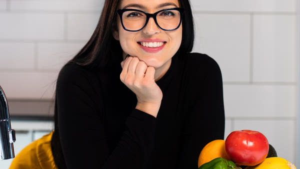 A wellness expert at a bright kitchen counter with fresh fruit in natural light