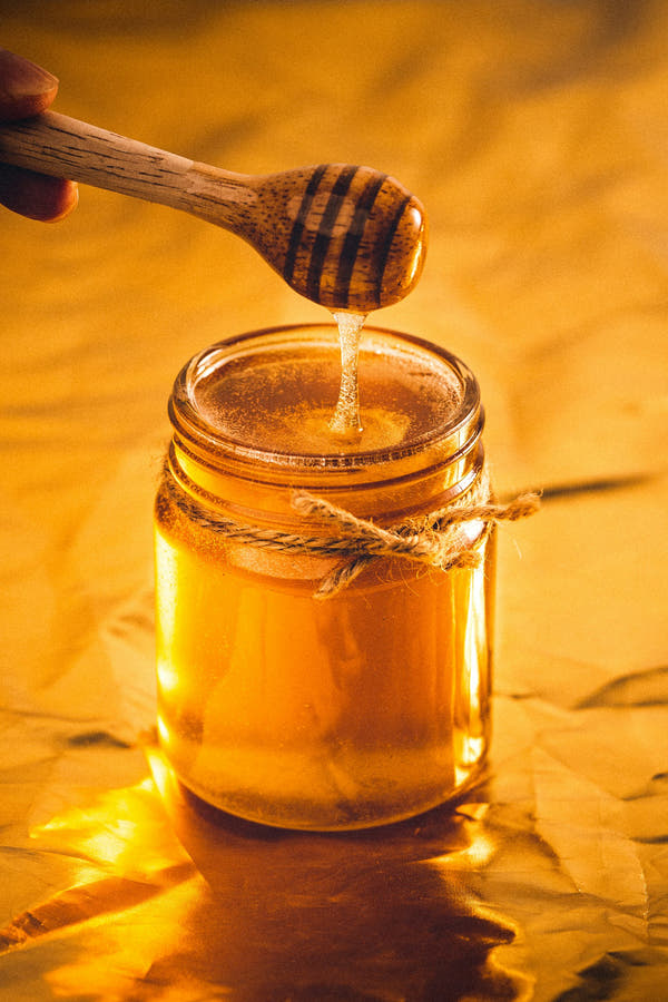 A jar of honey with a wooden dipper, a natural sweetener