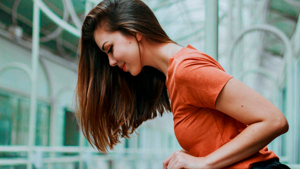 A woman holding her stomach, showing digestive discomfort