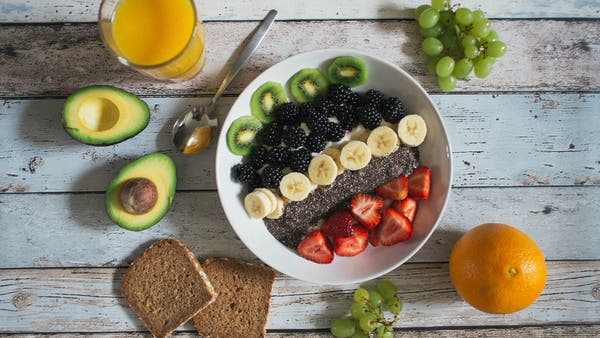 Flat-lay of everyday breakfast items including coffee, porridge and berries on a light surface