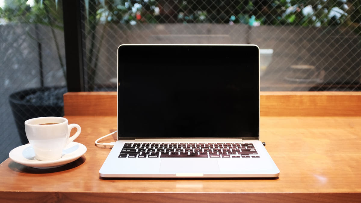A laptop on a warm kitchen desk suggesting online ordering, with a coffee nearby