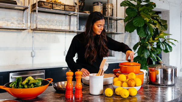A nutritionist at a clean kitchen counter with fresh food and a notebook in warm daylight