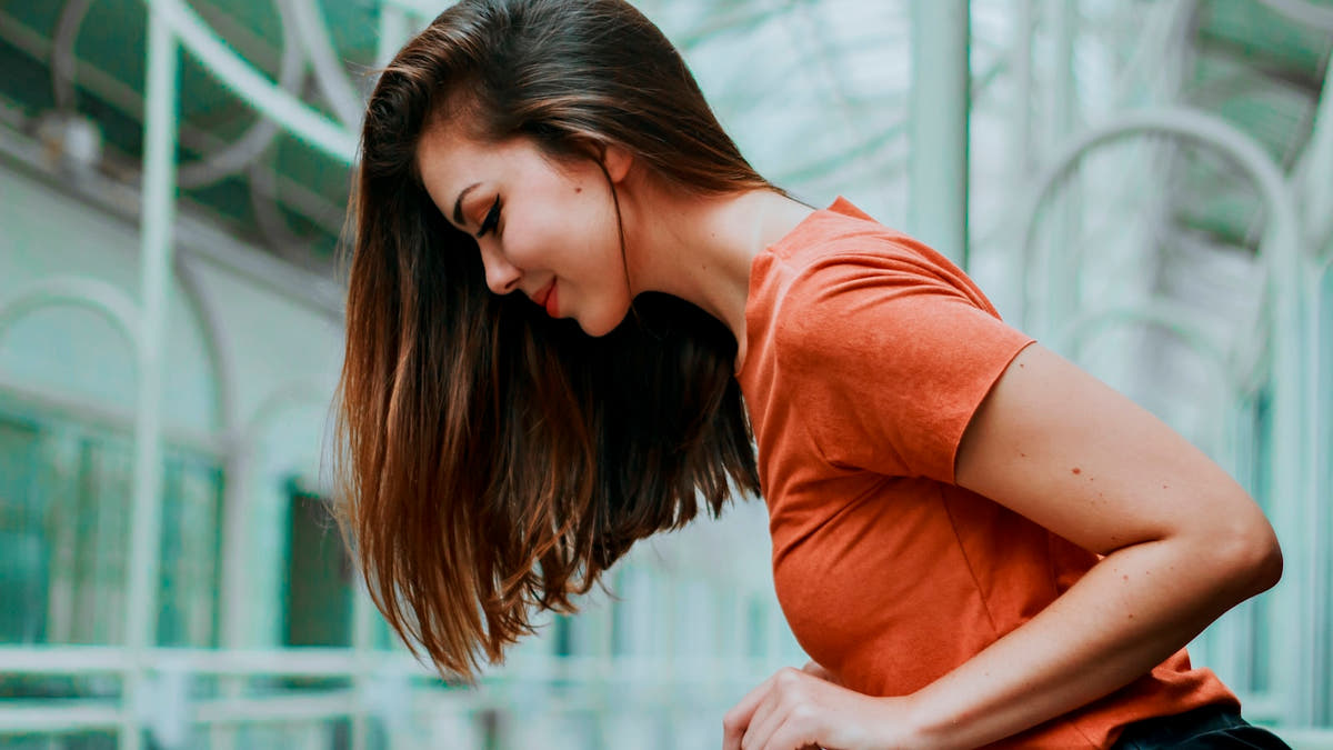 A woman holding her stomach, showing digestive discomfort