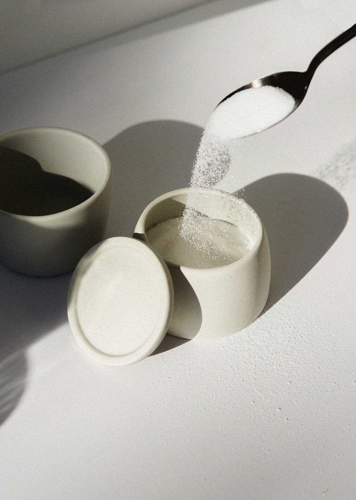 Small ceramic pots of white powdered sweeteners side by side for comparison