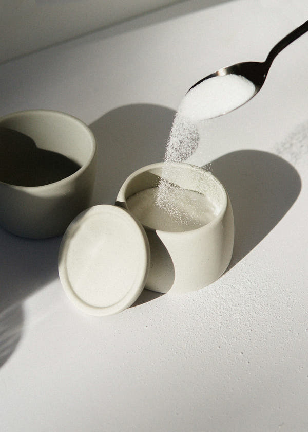 Small ceramic pots of white powdered sweeteners side by side for comparison