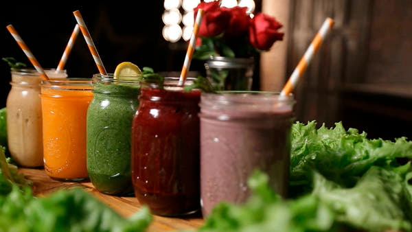 A row of colourful fresh smoothies in glass jars