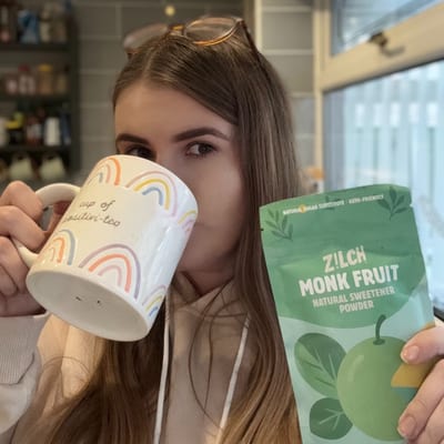 Courtney drinking from a mug and holding a pack of Zilch monk fruit sweetener
